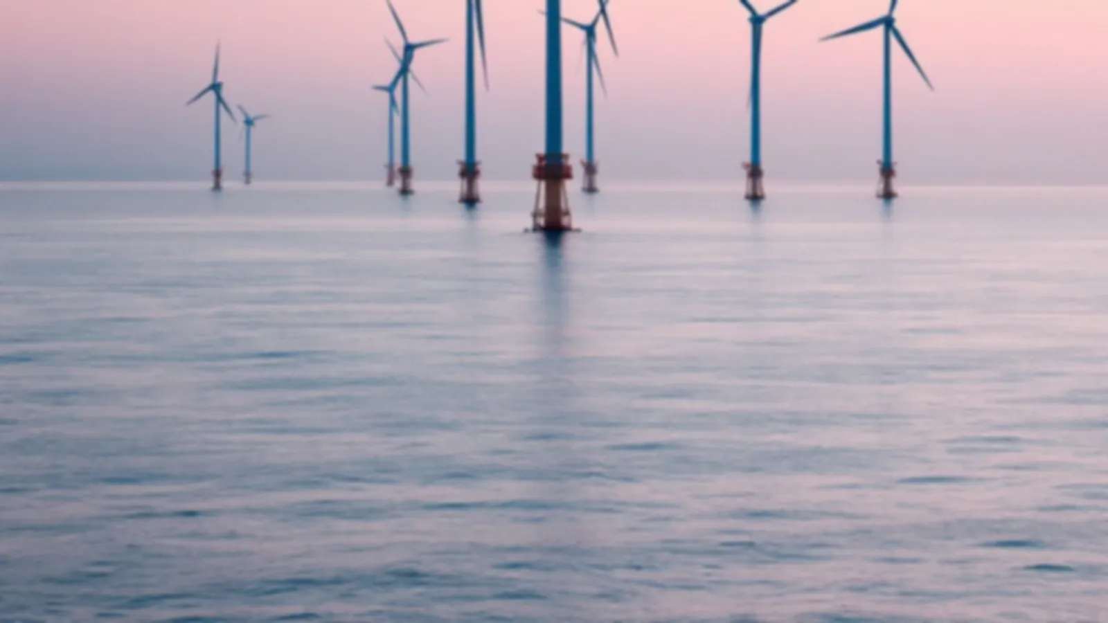 Offshore wind turbines standing in a calm silver sea at dawn with a soft pink horizon, the RotorQuotes view of bad credit loans, $100 – $5,000